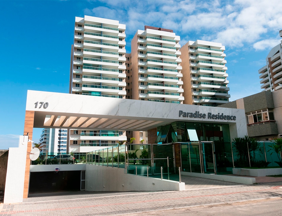 Entrada principal do Paradise Residence com portaria moderna e distintivo do empreendimento.
