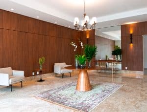 Hall social sofisticado do Paradise Residence com mobiliário elegante e acabamentos em madeira.