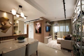 Interior de um apartamento decorado com uma paleta de cores neutras, realçado por iluminação moderna e peças decorativas elegantes. A sala de estar se abre para uma varanda iluminada, criando um espaço acolhedor e refinado.