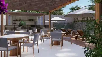 Área de piscina do Jaguaribe OCEAN SIDE com mesas de jantar elegantes, espreguiçadeiras de madeira, guarda-sóis grandes e uma cozinha ao ar livre, tudo sob uma estrutura de madeira moderna e aconchegante.
