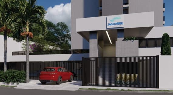 Entrada principal do edifício Jaguaribe OCEAN SIDE com portões elegantes, um carro vermelho à frente, e paisagismo tropical complementando sua arquitetura moderna.