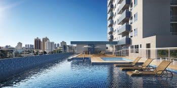 Uma piscina de borda infinita no terraço de um prédio com espreguiçadeiras e vista urbana panorâmica.