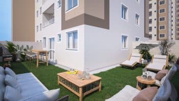 Área externa privativa de um apartamento com gramado, mobiliário de jardim e guarda-sol.