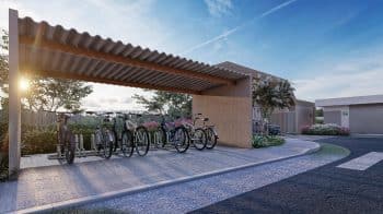 Bicicletário coberto com várias bicicletas estacionadas, localizado no DUO Residencial das Árvores, iluminado por um pôr do sol suave.