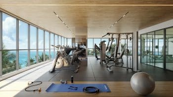 Interior da academia no BOSSA Farol de Itapoan, espaçosa e moderna, com equipamentos de ginástica voltados para amplas janelas que oferecem uma vista deslumbrante do oceano e do farol.