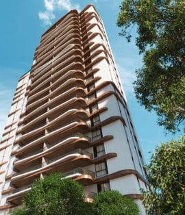 Perspectiva ascendente de um edifício alto com varandas curvas de madeira, destacando-se contra um céu azul claro e rodeado por vegetação.