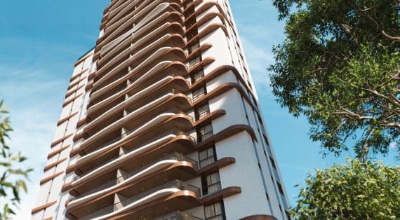 Perspectiva ascendente de um edifício alto com varandas curvas de madeira, destacando-se contra um céu azul claro e rodeado por vegetação.