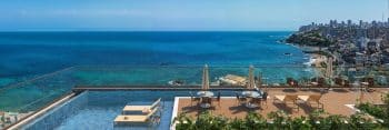 Imagem de uma piscina de borda infinita no rooftop do Rivê, com vista para o vasto oceano azul e a linha costeira de Salvador.