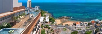 Imagem de uma piscina de borda infinita no rooftop do Rivê, com vista para o oceano azul e a linha do horizonte da cidade.