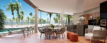 Vista do espaço gourmet ao ar livre no BOSSA Farol de Itapoan, com mobiliário elegante sobre um deck de madeira, uma piscina adjacente e uma vista panorâmica para uma praia com palmeiras.