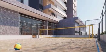 Quadra de esportes de areia do Villaggio Jardins, com rede de vôlei, cercada por uma grade e edifícios modernos ao fundo.