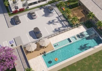 Imagem aérea do Jardim Patamares, em Salvador, mostrando o estacionamento, a piscina com espreguiçadeiras, mesas com guarda-sóis e uma área de lazer infantil.