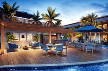 Imagem do Espaço Gourmet e deck seco do Oahu Itacimirim, mostrando mesas com guarda-sóis, cadeiras confortáveis, decoração moderna e iluminação acolhedora ao entardecer.