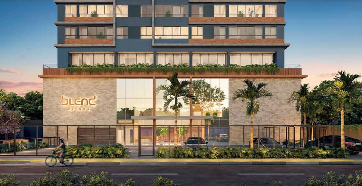 Fachada do Blend Pituba com detalhes modernos e porte-cochère, cercado por paisagismo e plantas tropicais.