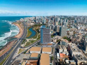 Vista aérea do empreendimento Ocean Breeze localizado no bairro Costa Azul, Salvador, mostrando a proximidade com a orla marítima e áreas urbanas.