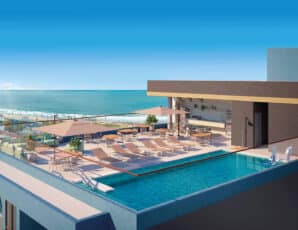 Rooftop panorâmico do Ocean Breeze, com piscina, espreguiçadeiras, mesas, guarda-sóis e uma vista deslumbrante para o oceano.