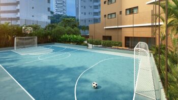 Quadra poliesportiva do Elleve Horto com traves, tabela de basquete e cercado de vegetação tropical, em área externa do condomínio