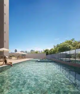 Piscina adulto com deck e espreguiçadeiras no Sevilha Residencial, cercada por vegetação e vista urbana