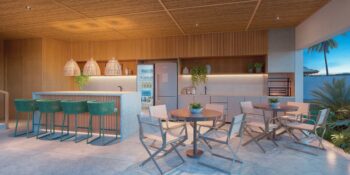 Espaço gourmet integrado à piscina no ZN Itacim, com bancada iluminada, cadeiras altas, mesas com cadeiras dobráveis e decoração tropical elegante.