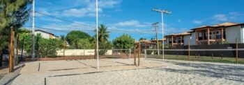 Quadra de beach tênis ao ar livre em Itacimirim, com rede montada, areia clara e iluminação, localizada próxima ao ZN Itacim.