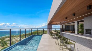 Área de lazer no rooftop do Residencial Ilha de Maui com piscina de borda infinita, deck molhado, bar e vista panorâmica para o mar.