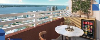 Varanda decorada do Residencial Eloisio Sobral da Silveira com vista para o rio, mesa redonda, frigobar e painel verde vertical.