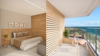 Studio do Residencial Ilha de Maui com divisória ripada, cama de casal, mesa na varanda e vista panorâmica para o mar.