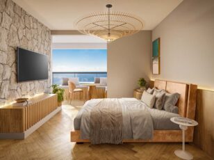 Studio decorado do Residencial Ilha de Maui com cama de casal, parede de pedra, varanda com vista para o mar e mobiliário em madeira clara.