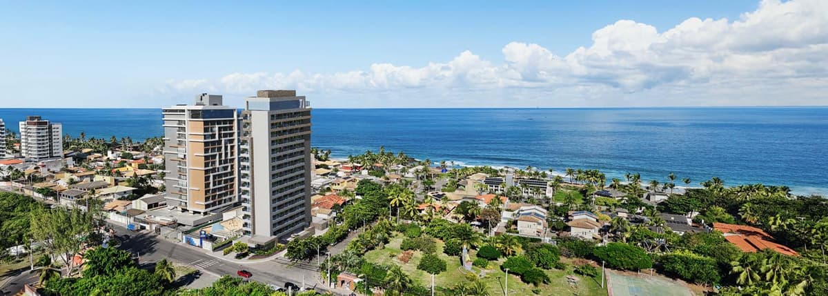 Imagem aérea do Residencial Ilha de Maui em Salvador, com vista para o mar e entorno arborizado da Praia da Pedra do Sal.