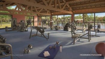Perspectiva interna da academia flutuante do Riviera Praia do Forte, com equipamentos modernos de musculação e cardio e vista para a lagoa.