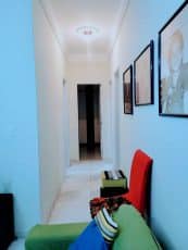 Corredor interno do apartamento usado 3 quartos no Garcia, com piso em mármore claro, iluminação no teto e paredes decoradas com quadros.