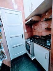 Cozinha compacta de apartamento usado no Garcia, Salvador, com armários planejados, fogão, pia em granito e piso em mármore.