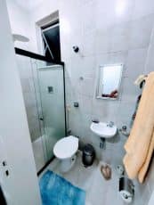 Banheiro da dependência do apartamento usado 3 quartos no Garcia, com box de vidro, vaso sanitário, pia compacta e revestimento cerâmico.