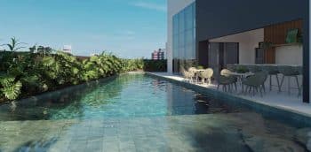 Perspectiva da piscina com deck molhado do NEST Rio Vermelho, área de lazer moderna com espaço de convivência e paisagismo integrado.
