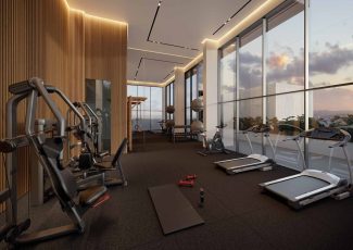 Perspectiva da academia do NEST Rio Vermelho, equipada com esteiras, bicicletas, aparelhos modernos e ampla vista envidraçada.