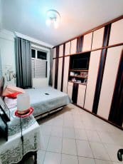 Quarto suíte do apartamento usado 3 quartos no Garcia, em Salvador, com cama de casal, cortinas e armários planejados com espaço para TV.