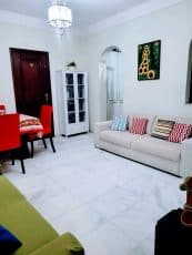 Sala do apartamento usado 3 quartos no Garcia, em Salvador, com sofás, mesa de jantar, piso em mármore claro e decoração aconchegante.