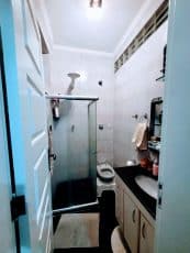 Banheiro da suíte do apartamento usado 3 quartos no Garcia, em Salvador, com box de vidro, bancada em granito e armário planejado.
