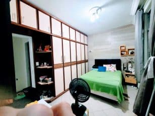 Suíte do apartamento usado 3 quartos no Garcia, em Salvador, com cama de casal, armários planejados de parede inteira e cortinas.