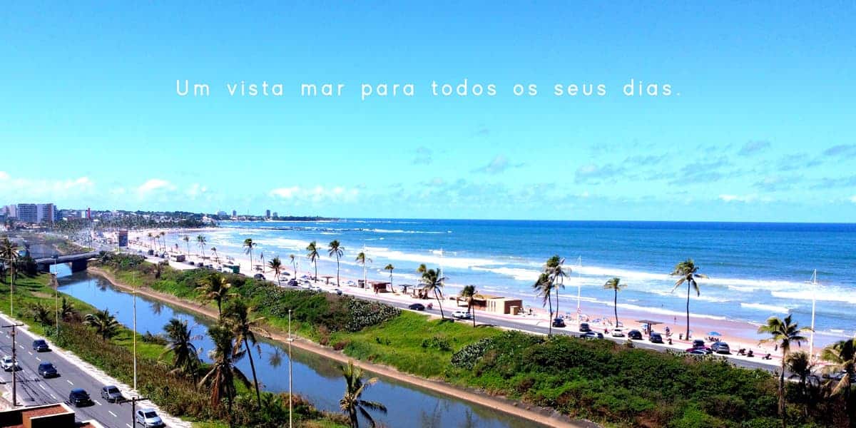 Vista aérea da orla de Jaguaribe, mostrando o mar azul, coqueiros e a ciclovia próxima ao Laut Jaguaribe em Salvador.