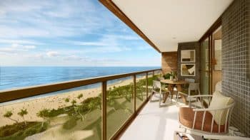 Varanda da planta tipo 04 do Laut Jaguaribe, com mesa de jantar, poltrona, decoração moderna e vista frontal para o mar de Jaguaribe.