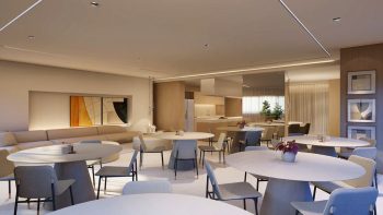 Salão de festas e lounge bar do Laut Jaguaribe, com mesas redondas, cadeiras elegantes, cozinha integrada e decoração contemporânea em tons claros e madeira.