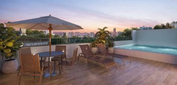 Terraço do Residencial Florença com piscina, espreguiçadeiras e vista para a cidade de Salvador ao pôr do sol.