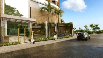 Entrada do Laut Jaguaribe em Salvador, com fachada moderna, paisagismo tropical, área de convivência e acesso elegante para pedestres e veículos.