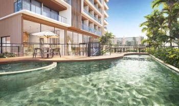 Piscina com deck molhado do Lumio Jardim Apipema em Salvador, com espreguiçadeiras, guarda-sóis e fachada moderna ao fundo.