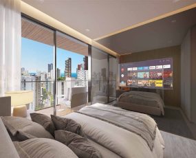 Suíte master do apartamento de 2 suítes do Lumio Jardim Apipema em Salvador, com varanda, cama queen, TV e vista panorâmica da cidade.