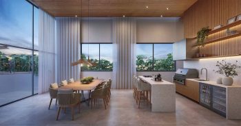 Lounge de festas do Lumio Jardim Apipema em Salvador, com mesa de jantar, cozinha gourmet e design moderno com acabamento em madeira.