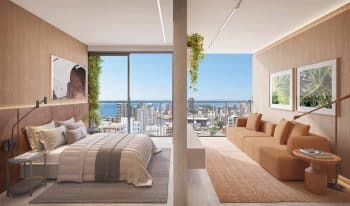 Apartamento quarto e sala do Lumio Jardim Apipema, com living integrado à varanda e vista panorâmica para o mar e a cidade de Salvador.