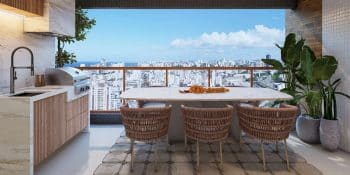 Varanda gourmet do Vivid Pituba com mesa, churrasqueira, bancada e vista panorâmica de Salvador