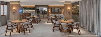 Salão de festas do Vivid Pituba com mesas redondas, bar integrado e decoração contemporânea